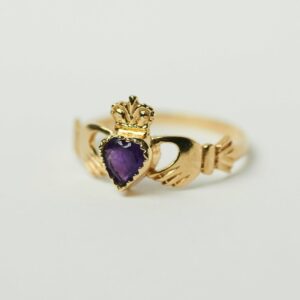 Gold ring with hands holding purple stone
